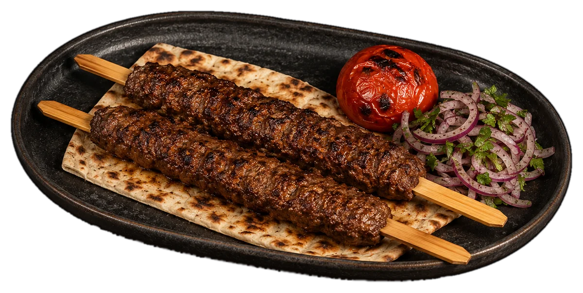 Two lula kabob skewers on grilled lavash with a blistered tomato and sumac onions